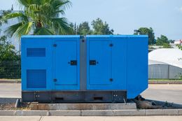 Blue generator on a concrete pad, outdoors.