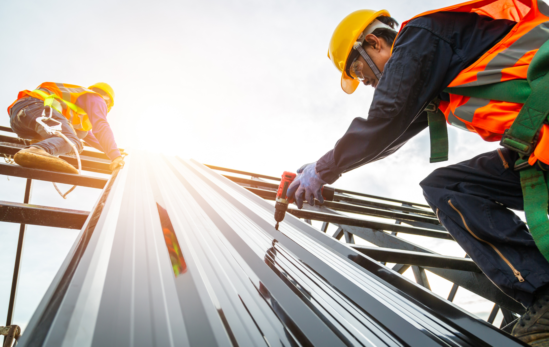 Two construction workers are working on the roof of a building.