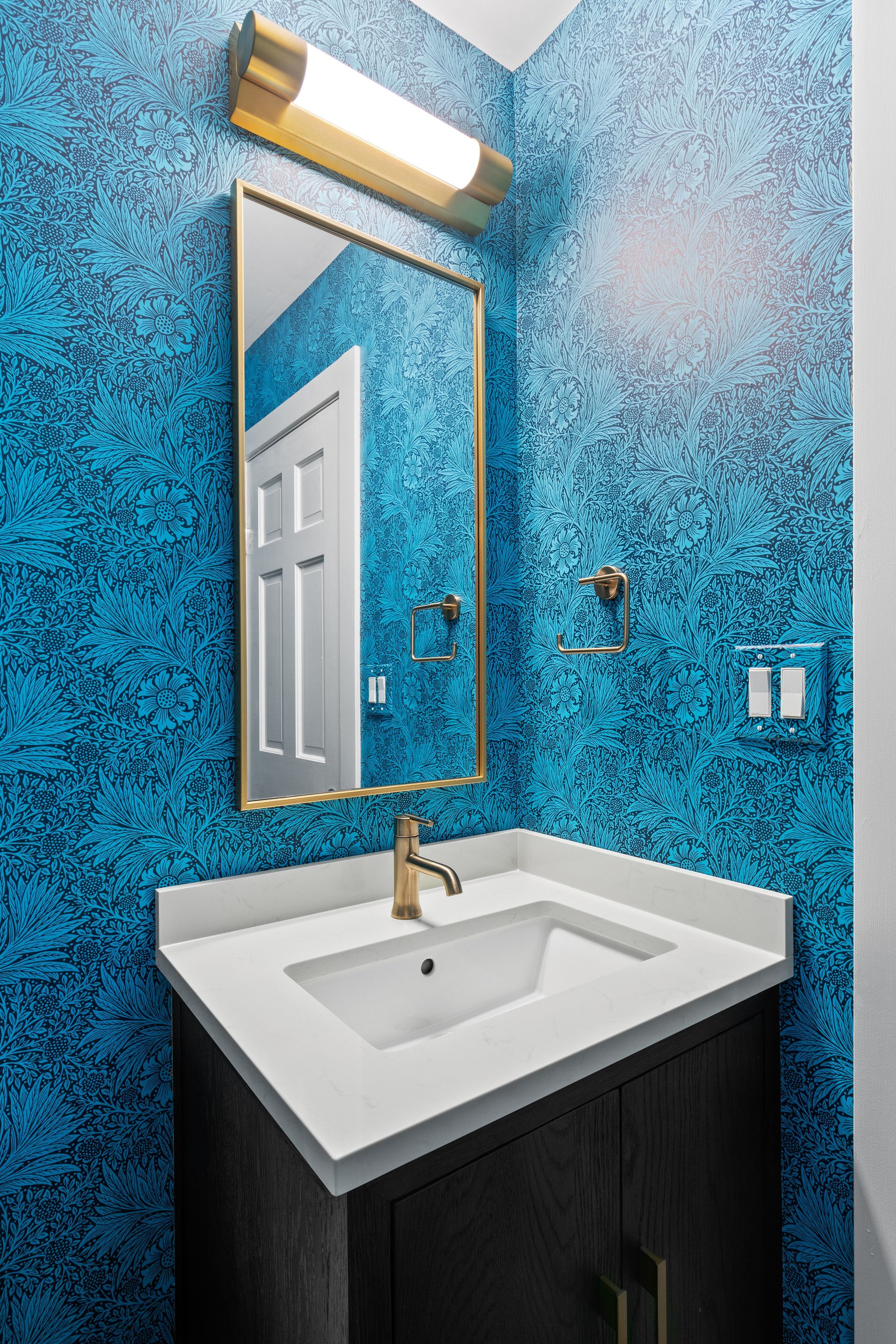A bathroom with a sink , mirror and blue walls.