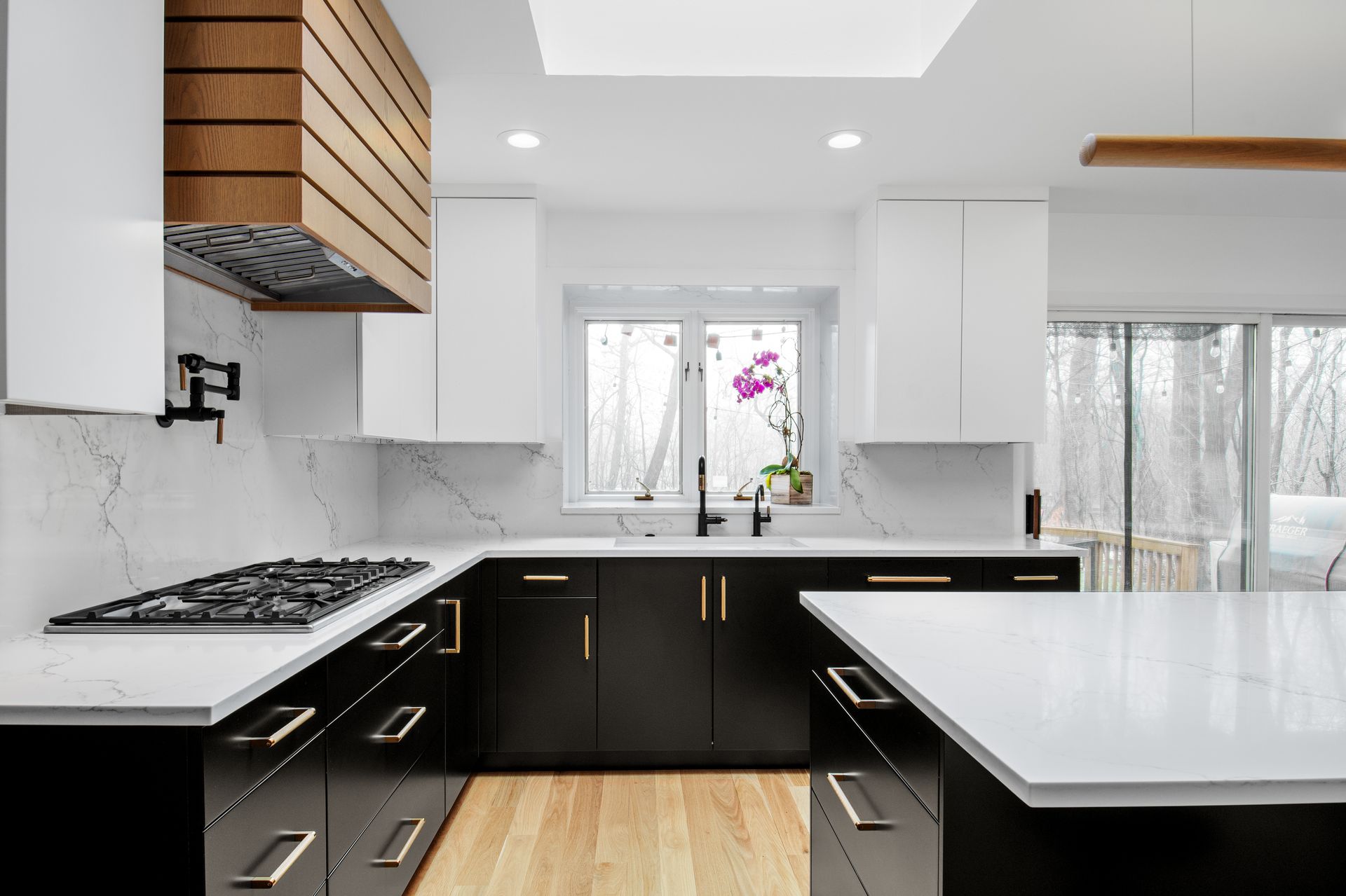 A kitchen with black cabinets and white counter tops and a stove top oven.