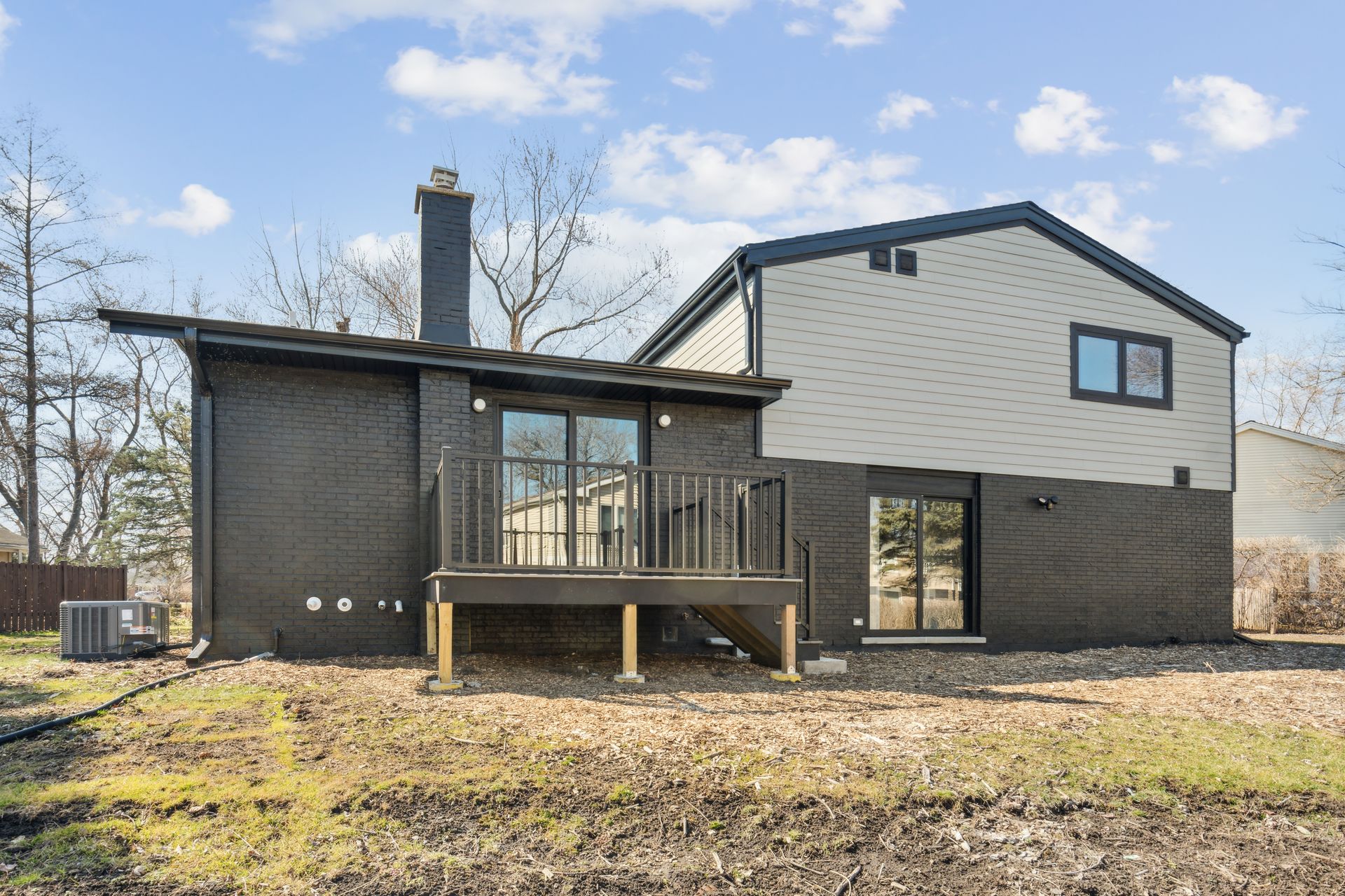 The back of a house with a deck and a chimney.