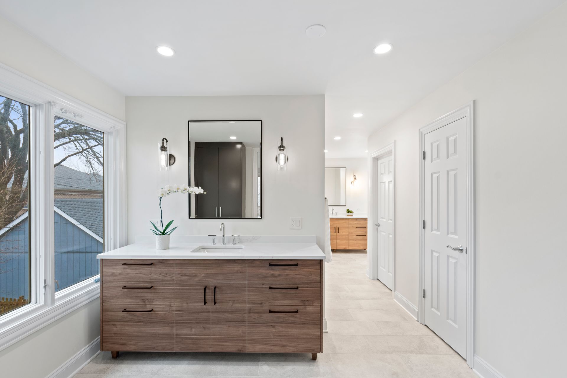 A bathroom with two sinks , a mirror , and a large window.