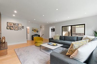 A living room with a couch , chair , coffee table and pictures on the wall.