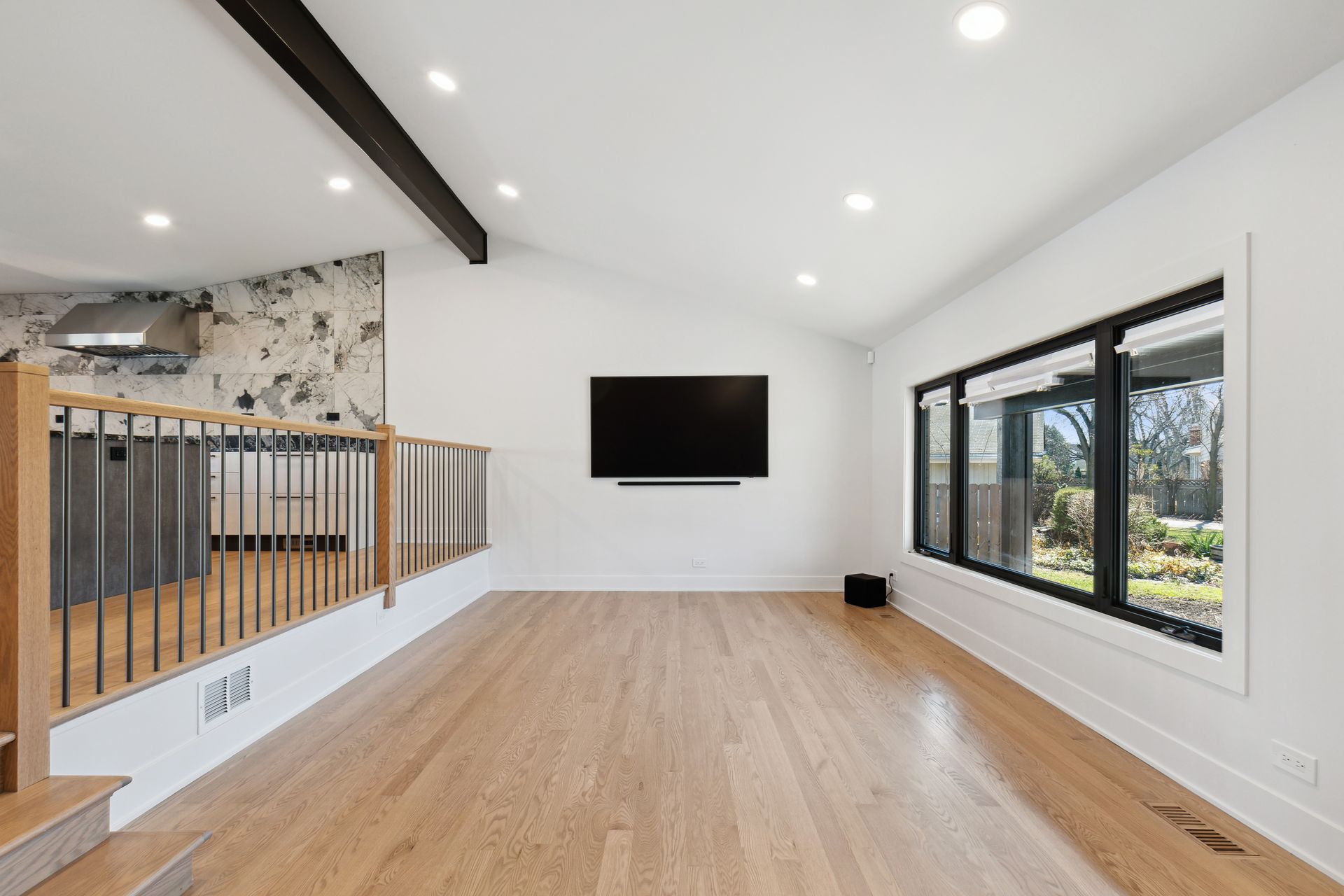 An empty living room with hardwood floors and a flat screen tv