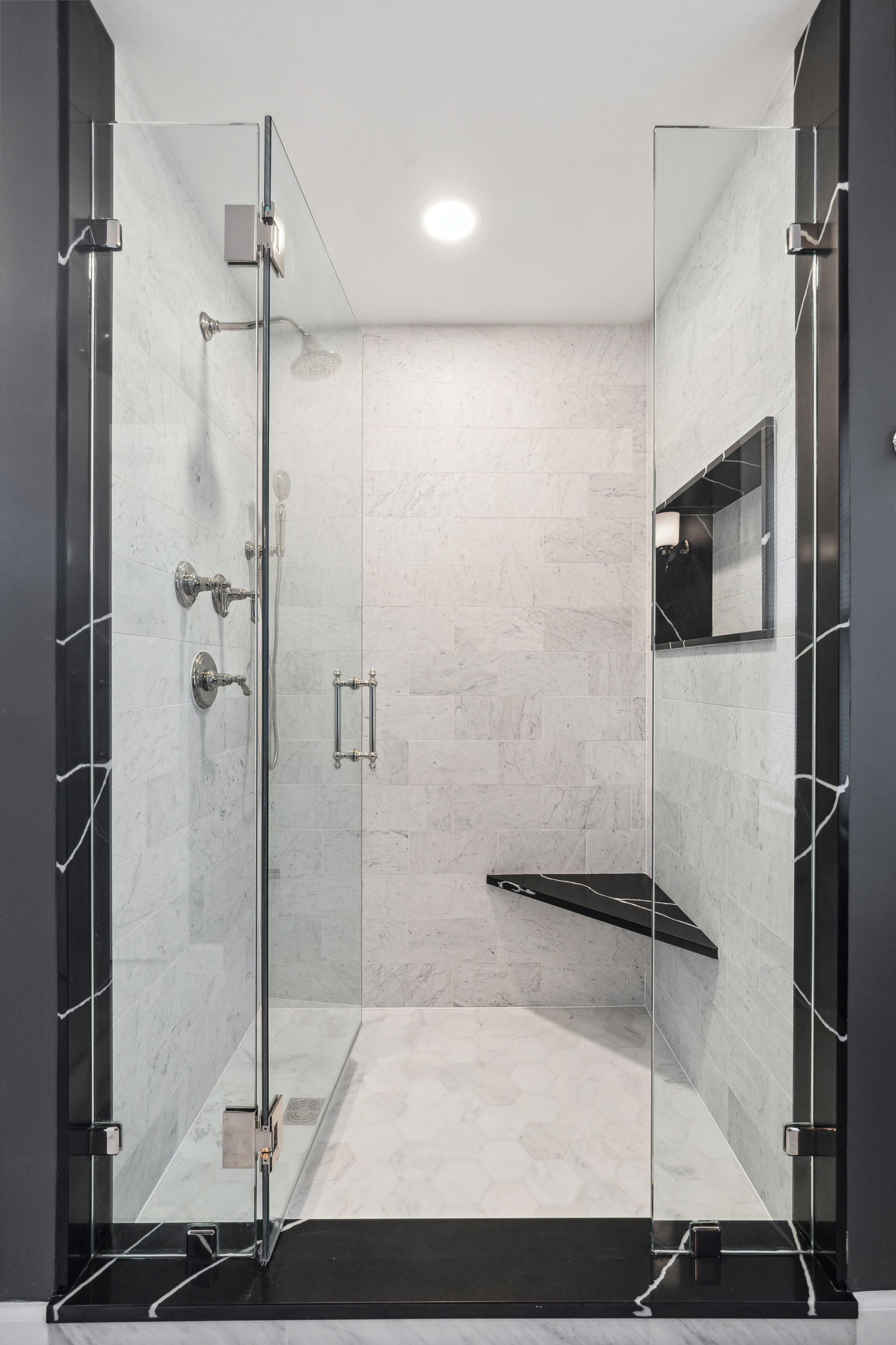 A bathroom with a walk in shower with a glass door.