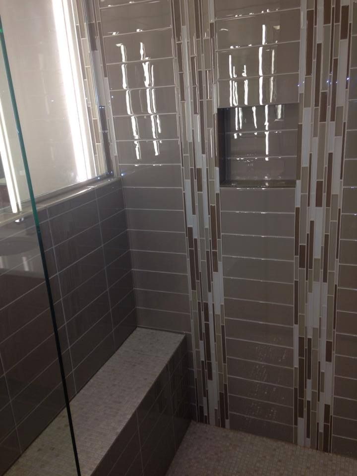 A bathroom with a walk in shower and a bench.