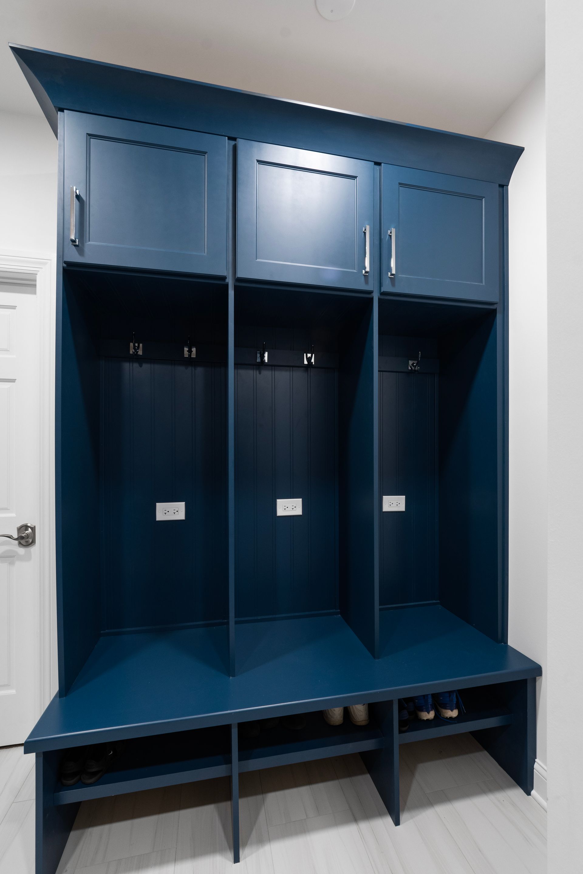 A blue locker with a bench and hooks in a hallway.