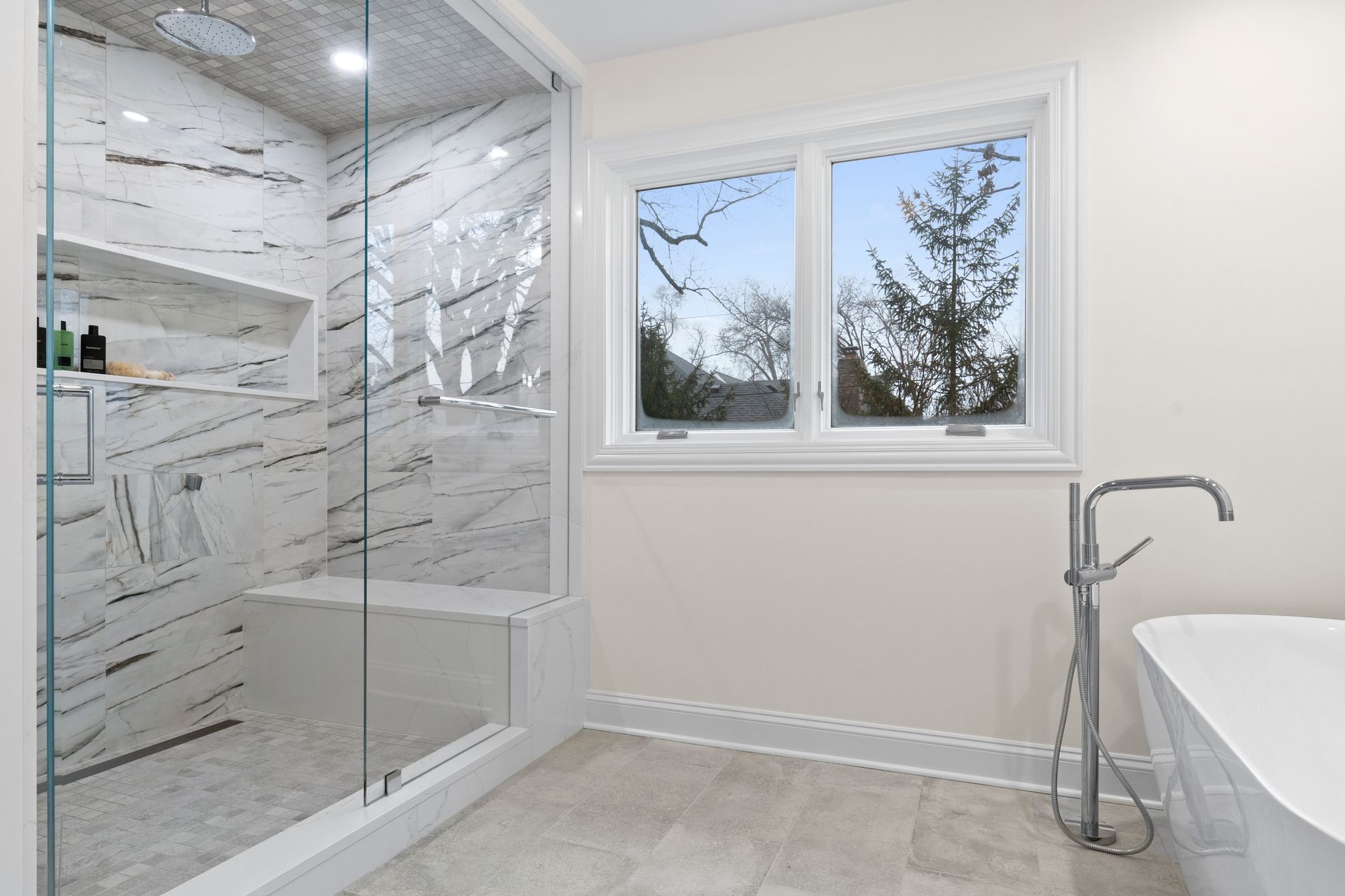 A bathroom with a walk in shower , tub and window.