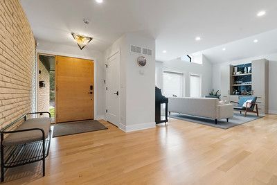 A living room with hardwood floors , a couch , chairs and a bench.