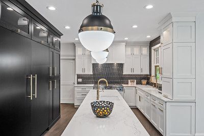 A kitchen with black cabinets and white cabinets and a large island in the middle.