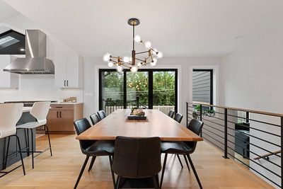A dining room with a long wooden table and chairs and a chandelier hanging from the ceiling.