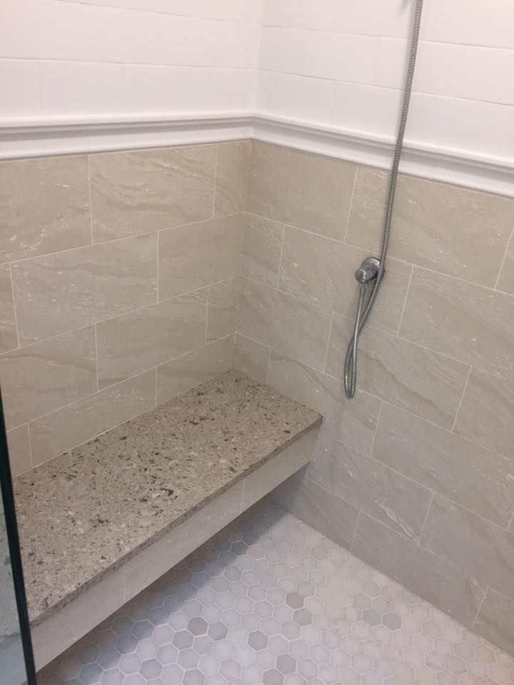A shower with a bench and a shower head.