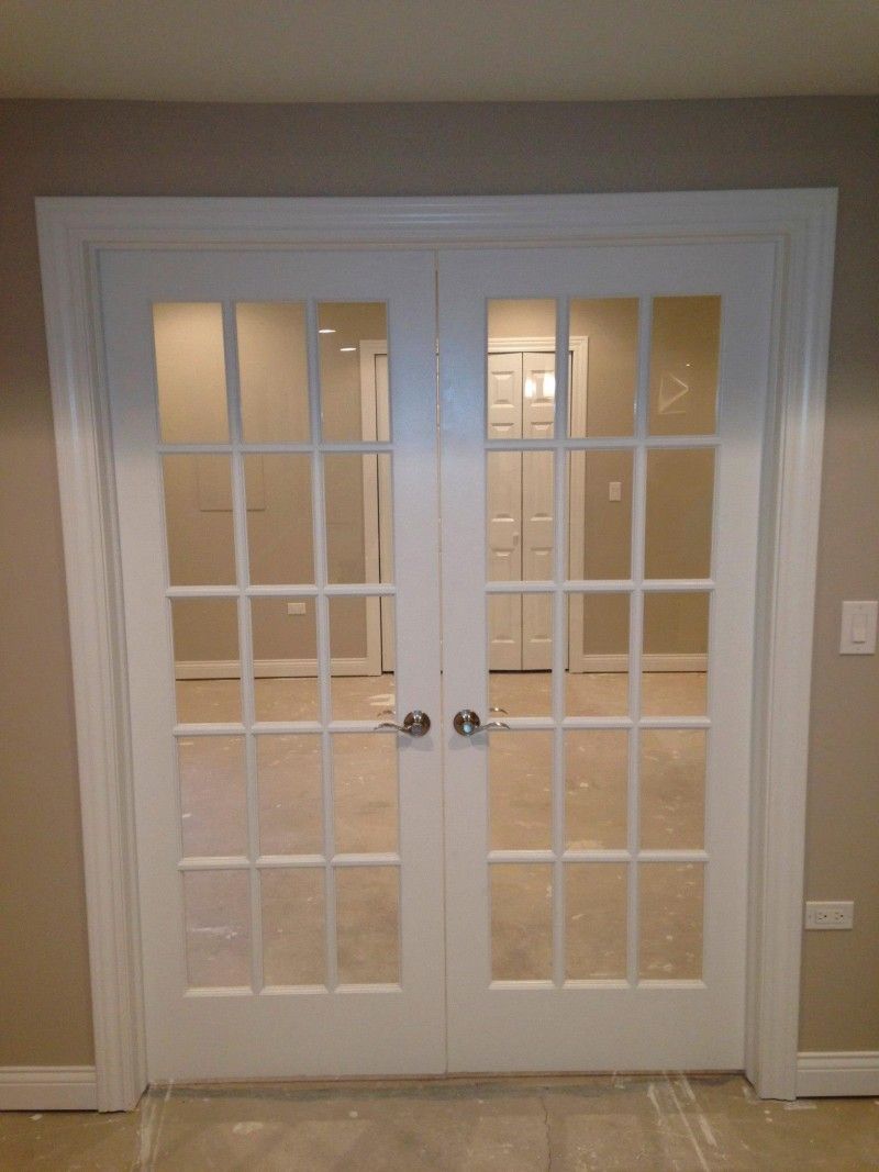 A pair of white french doors are open to a room.