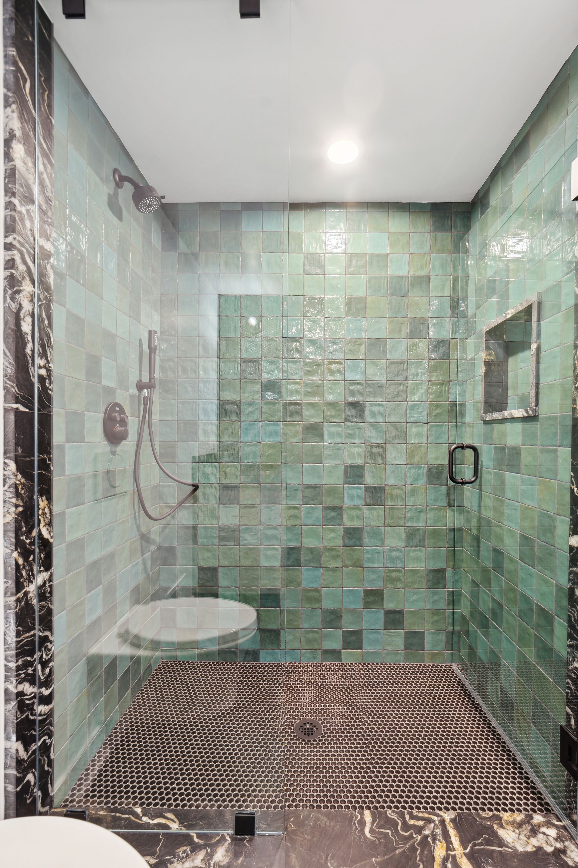 A bathroom with green tiles and a walk in shower.