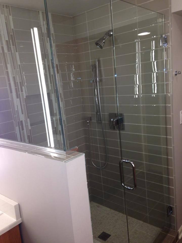 A bathroom with a walk in shower with a glass door.