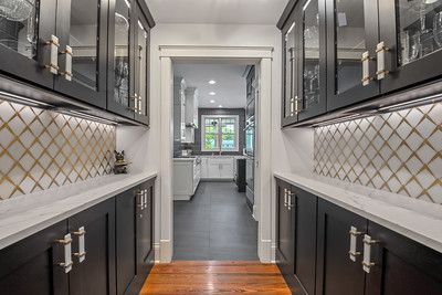 A kitchen with black cabinets and glass doors leading to a pantry.