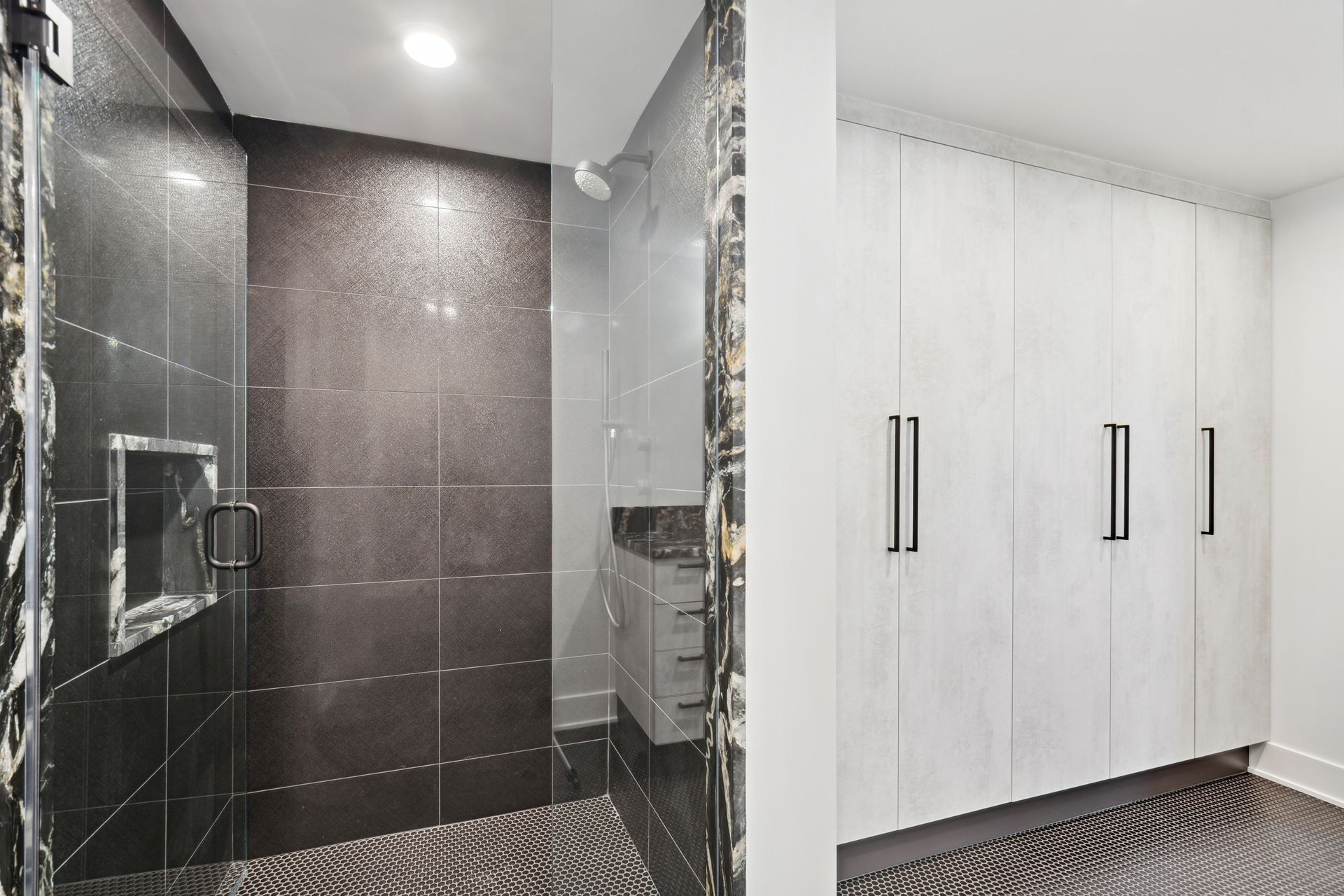 A bathroom with a walk in shower and white cabinets