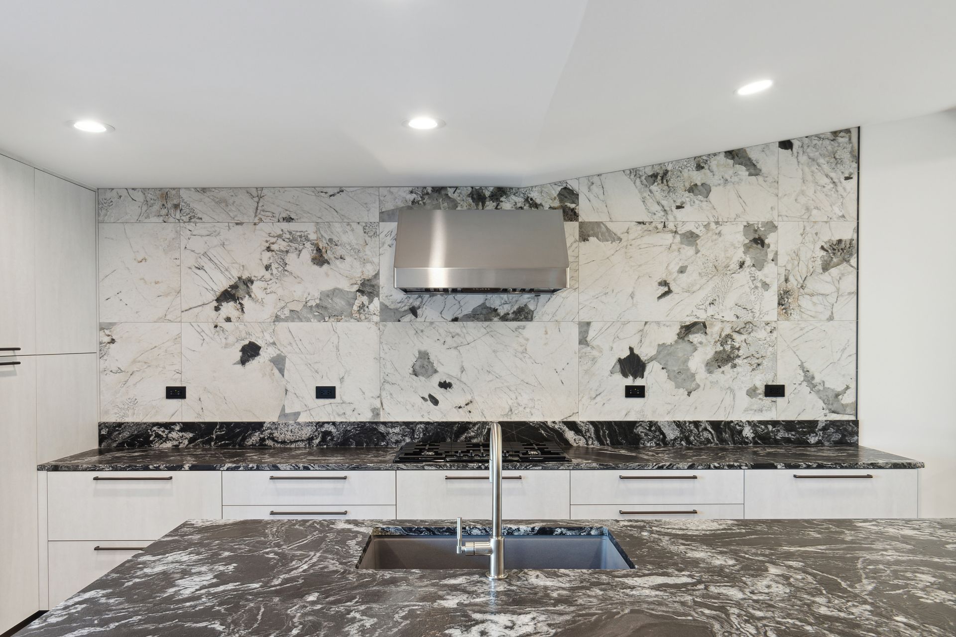 A kitchen with a sink and a stainless steel hood.