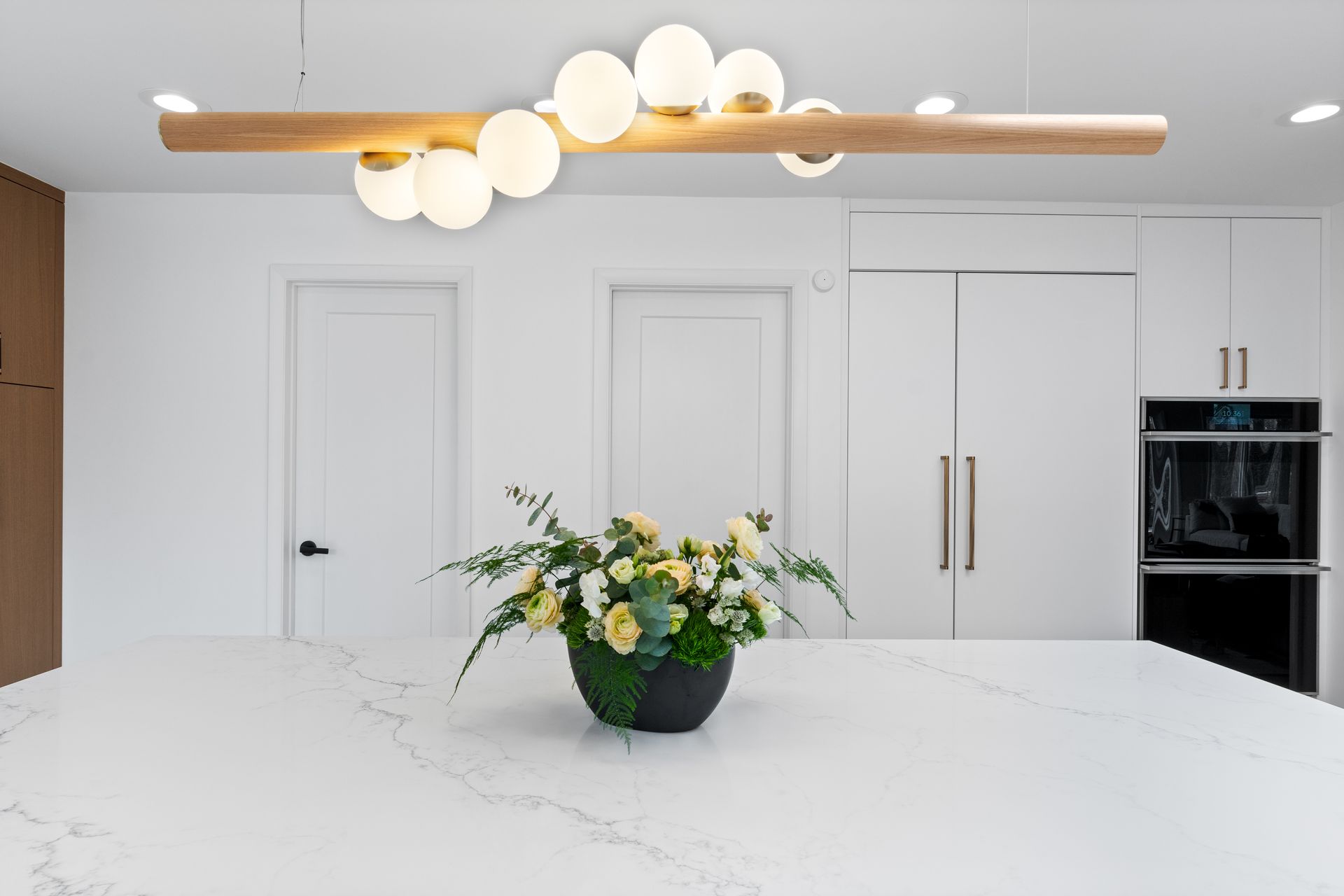 There is a vase of flowers on the counter in the kitchen.