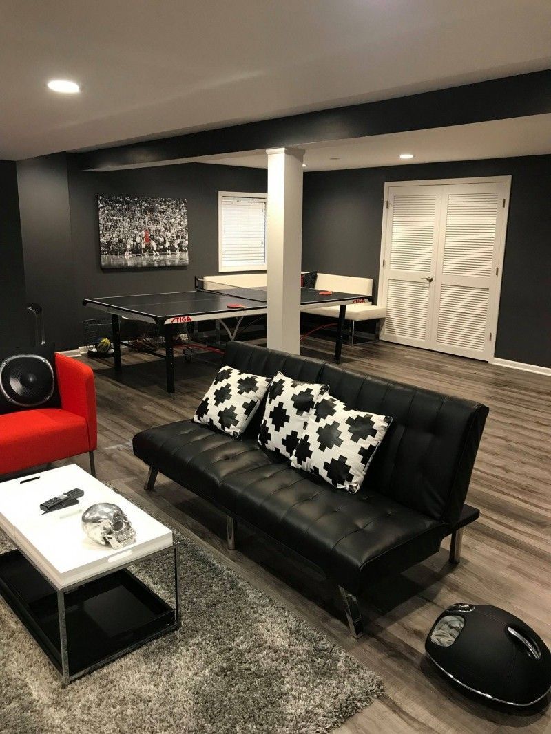 A living room with a black couch and a red chair.