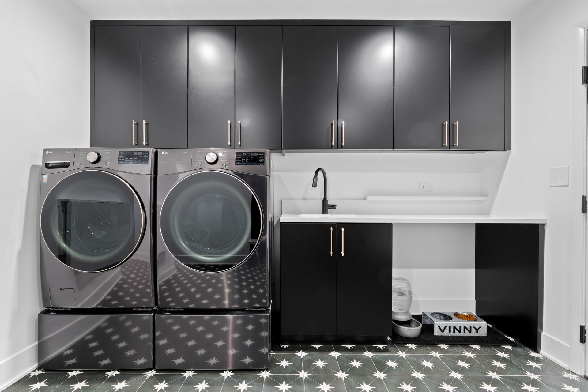 A laundry room with a washer and dryer and black cabinets.