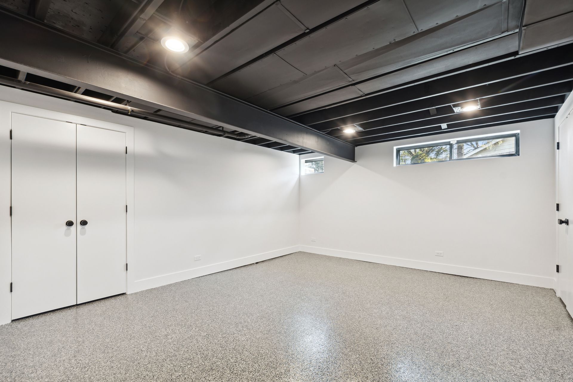An empty basement with white walls and a concrete floor.
