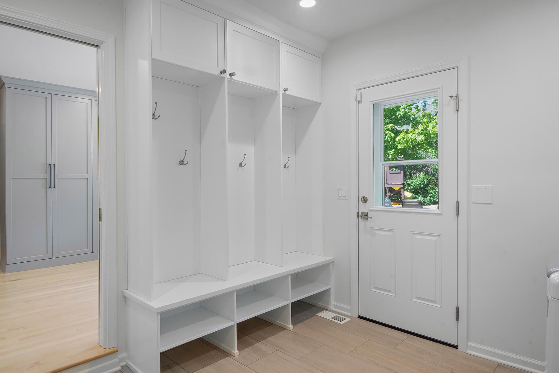 A white mud room with a bench and a window.