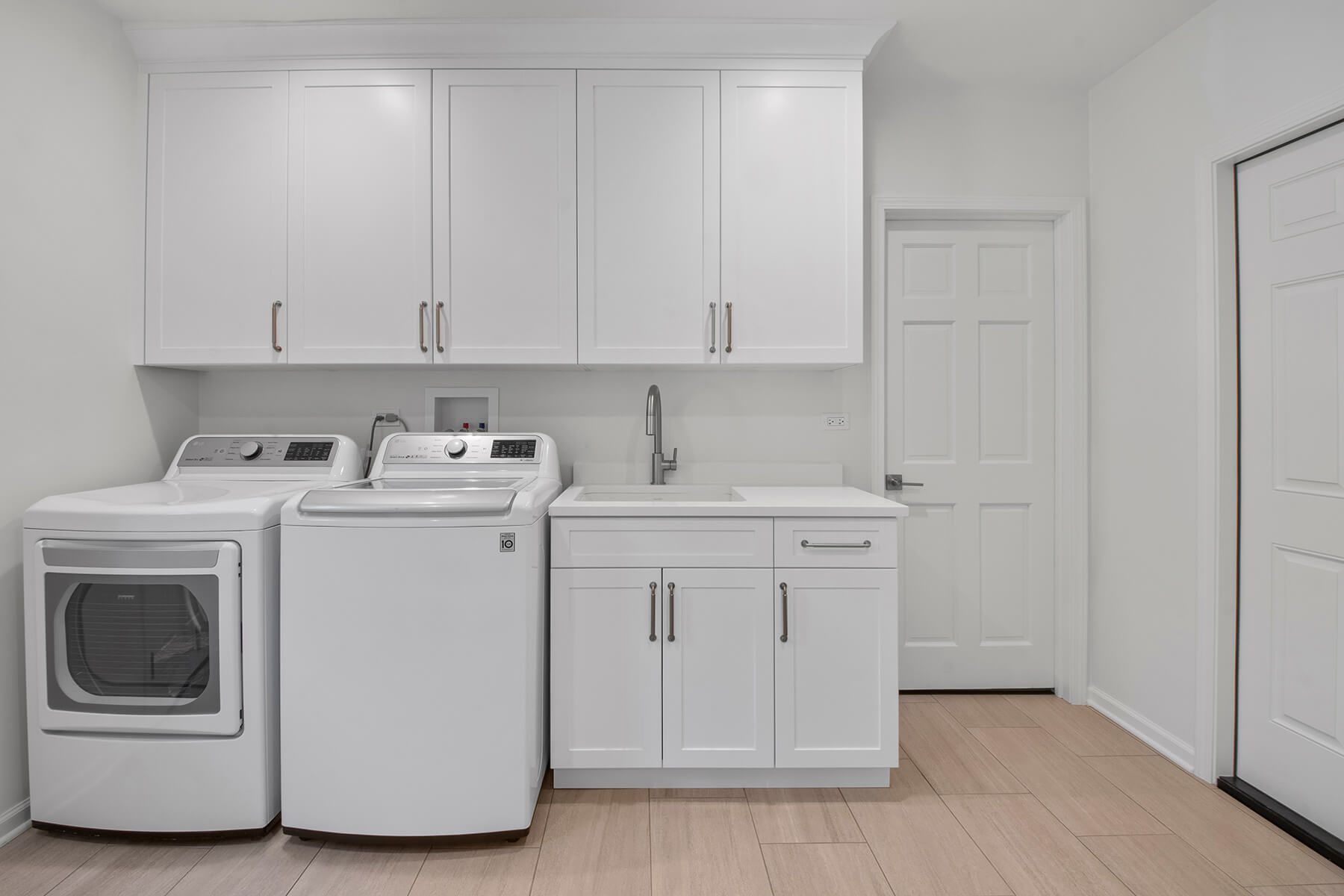 A laundry room with a washer and dryer , sink , and cabinets.