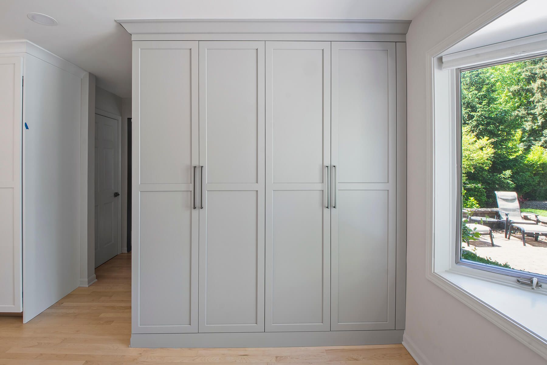 A room with a lot of white cabinets and a window.