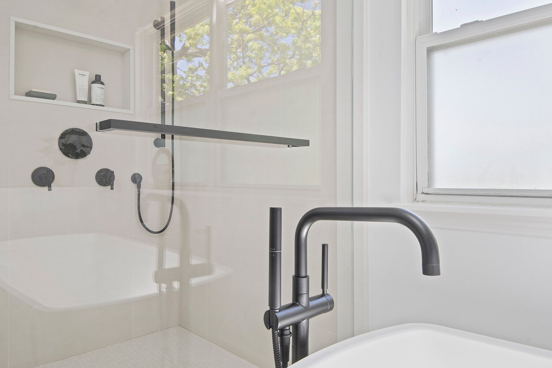 A bathroom with a bathtub , shower , and window.