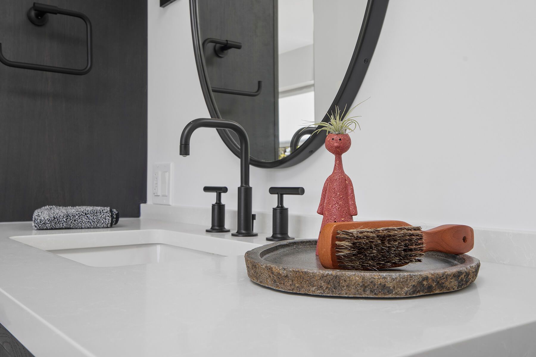 A bathroom vanity with a sink , mirror and brush on it.