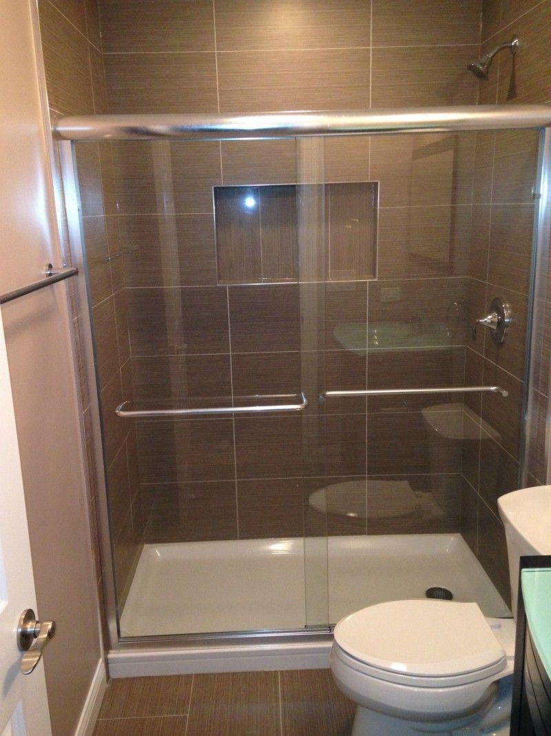 A bathroom with a toilet , shower , and sliding glass door.