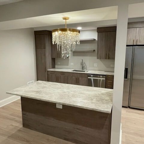 A kitchen with a large island and a chandelier hanging from the ceiling.