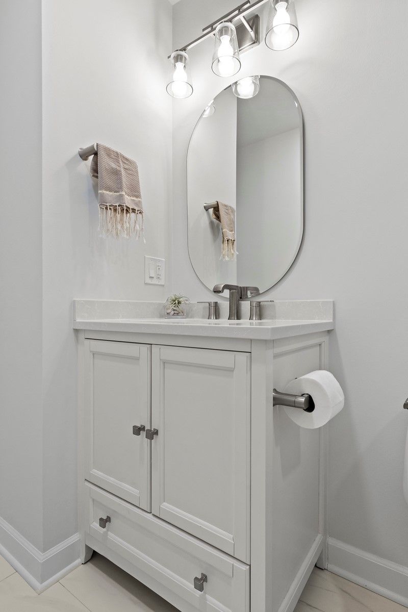 A bathroom with a sink , mirror and toilet paper.