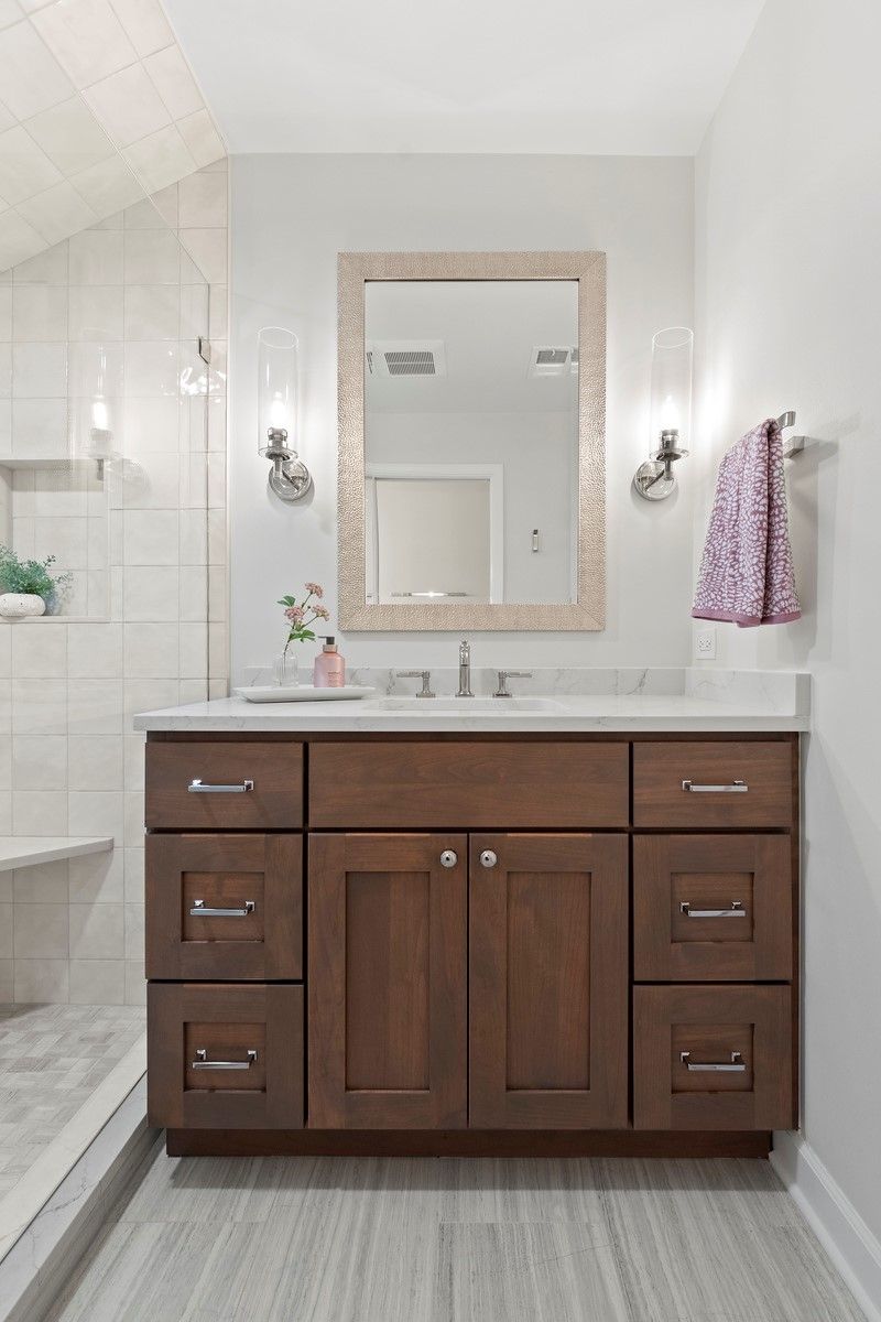 A bathroom with a sink , mirror and drawers.