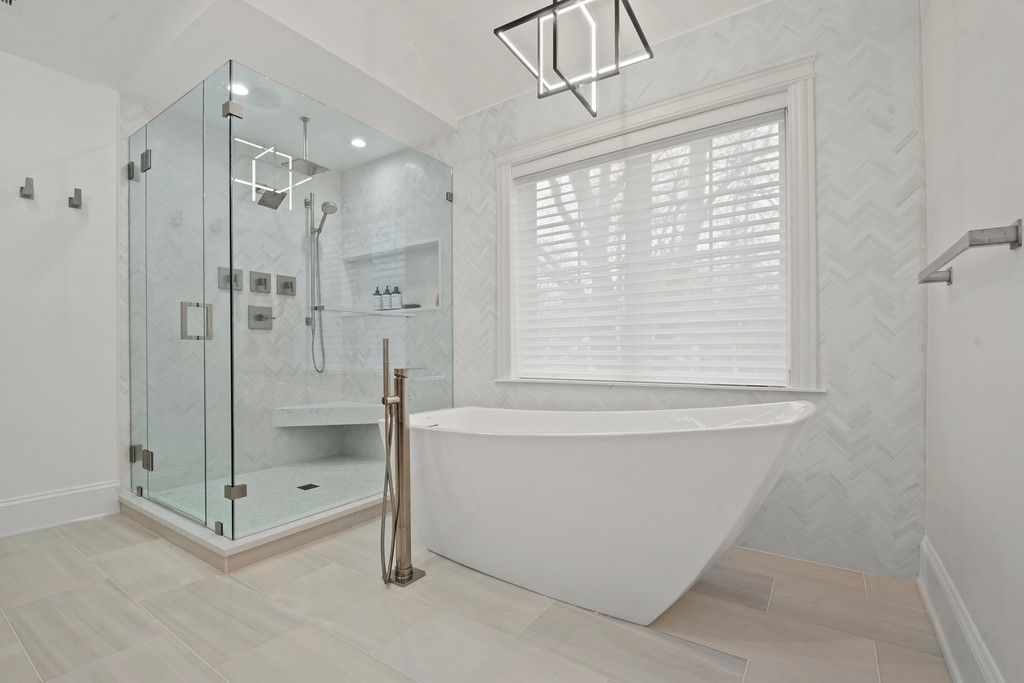 A bathroom with a tub , shower , and window.