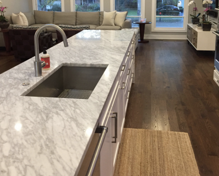 A kitchen with marble counter tops and a stainless steel sink