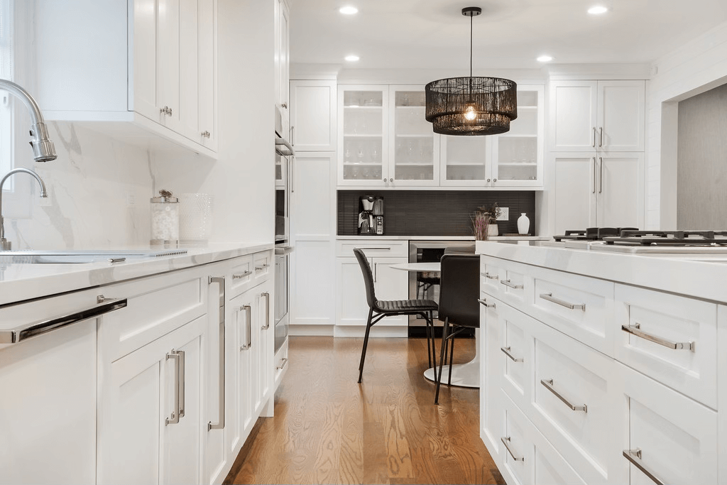 A kitchen with white cabinets and hardwood floors and a large island.