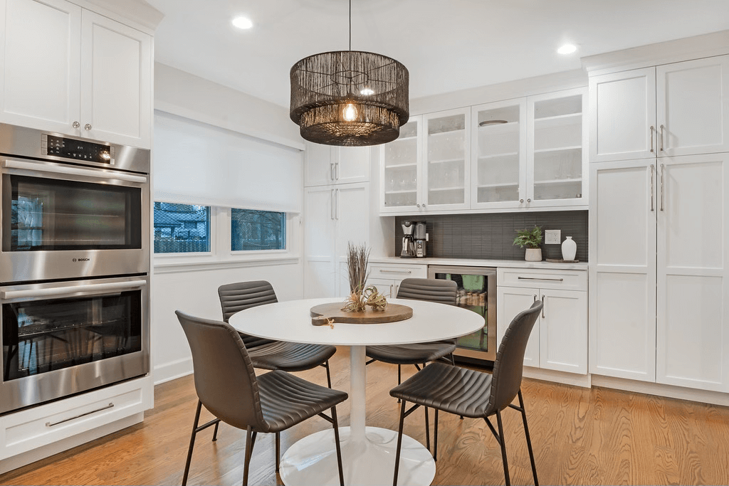 A kitchen with a round table and chairs and stainless steel appliances.