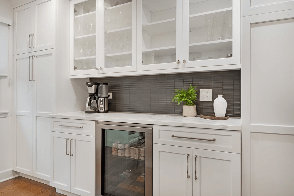 A kitchen with white cabinets , stainless steel appliances , and a wine cooler.