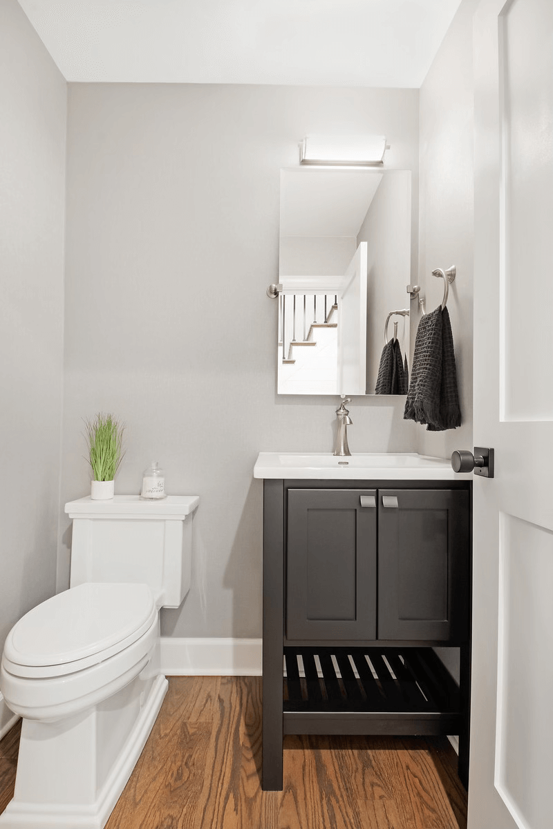 A bathroom with a toilet , sink and mirror.