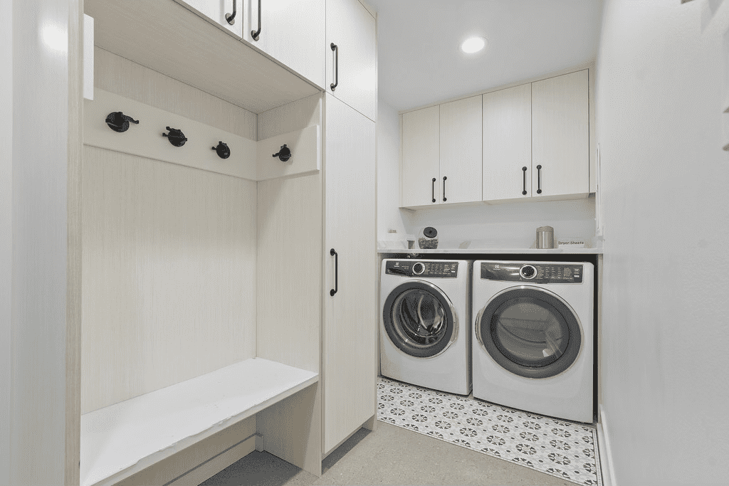 A laundry room with a washer and dryer and a bench.