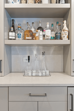 There are many bottles of alcohol on the shelves in this kitchen.