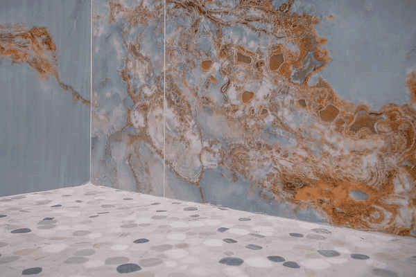 A bathroom with a marble wall and a tiled floor.