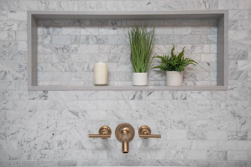 A bathroom with a sink and a shelf with potted plants and candles.