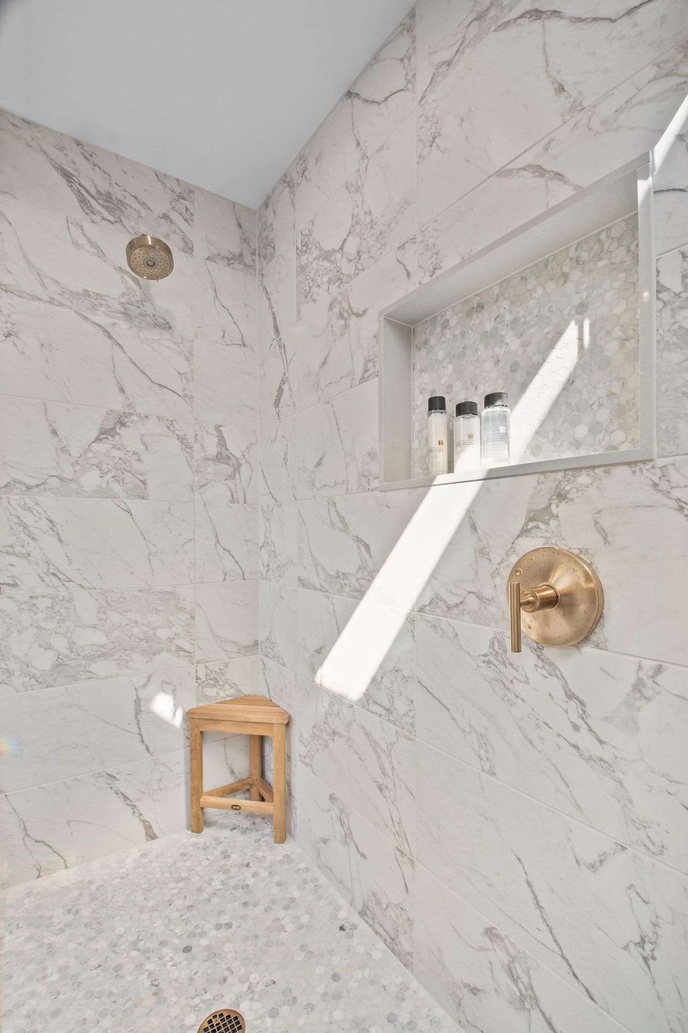 A bathroom with a shower , a stool , and a shelf.