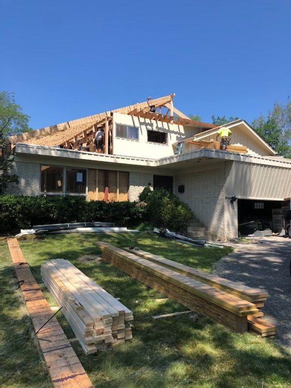 A house under construction with a lot of wood in front of it.