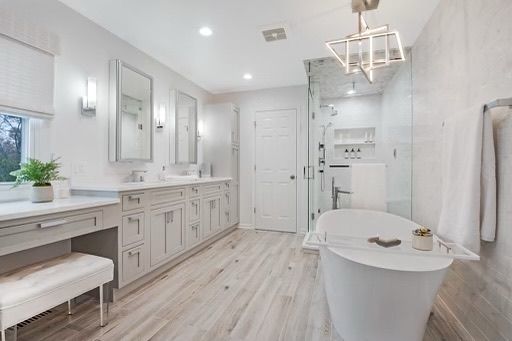 A bathroom with a tub , sinks , mirrors and a walk in shower.