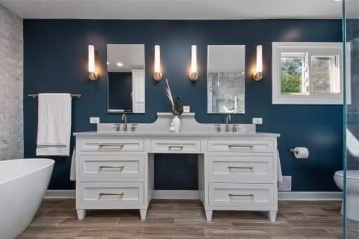 A bathroom with two sinks , two mirrors and a tub.