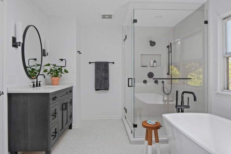 A bathroom with a tub , sink , mirror and shower.
